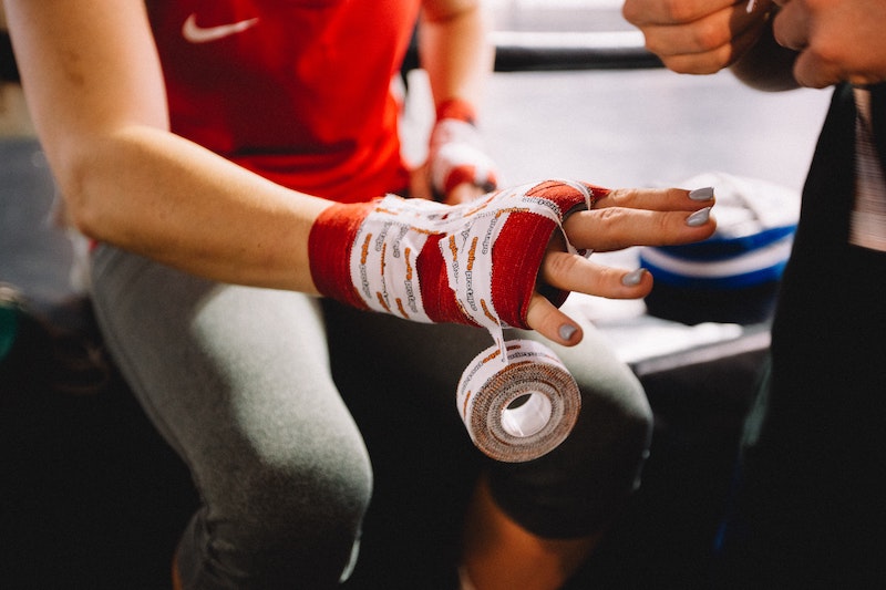 Female hand getting wrapped with medical tape.