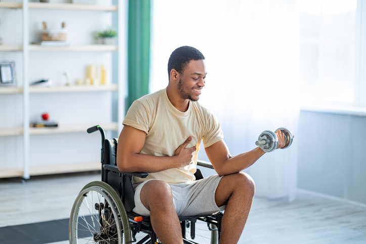 Man smiling in a wheelchair while lifting weights 