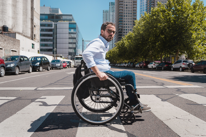 Adult man in a wheelchair crossing the street with caution