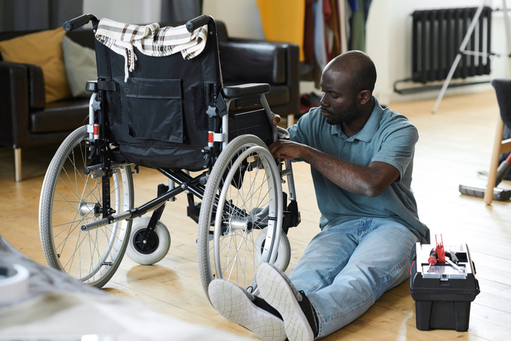 Disabled man fixing his wheelchair 