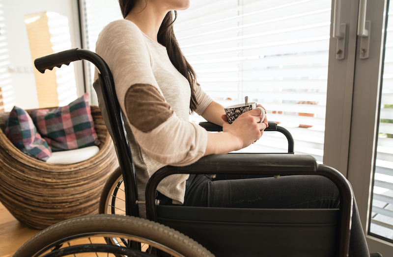 Young woman with a cup of tea sitting in a wheelchair